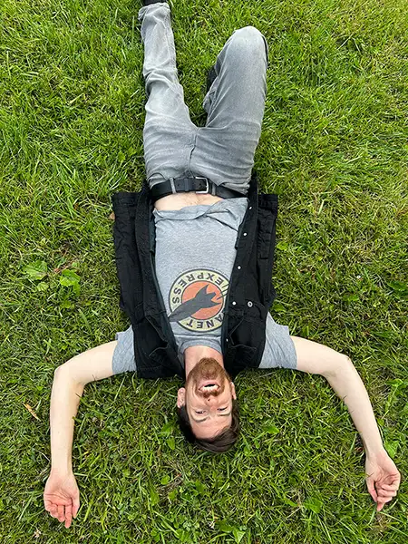 Kevin Murphy lays in the grass smiling and looking hirable